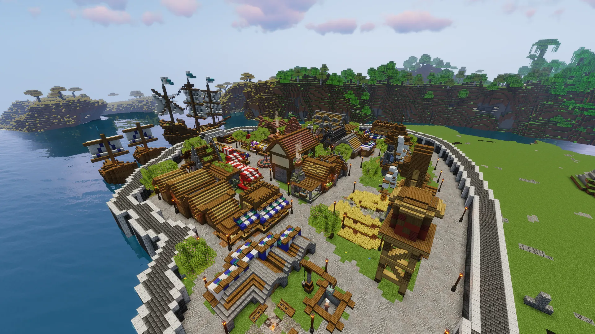 Город в Minecraft с высоты: прилавки, дома с деревянными крышами и поле пшеницы, за стеной — гавань с кораблями